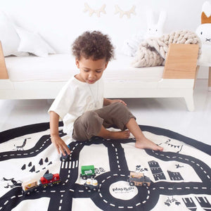 Enfant jouant avec des voitures miniatures sur le tapis de jeu circuit automobile