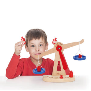 Enfant manipulant une balance à plateaux pour apprendre le poids