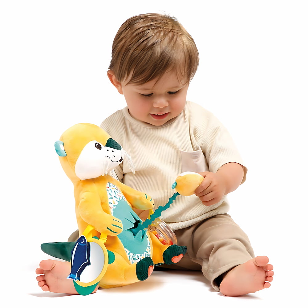 Bébé manipulant la peluche maman loutre pour développer sa motricité fine