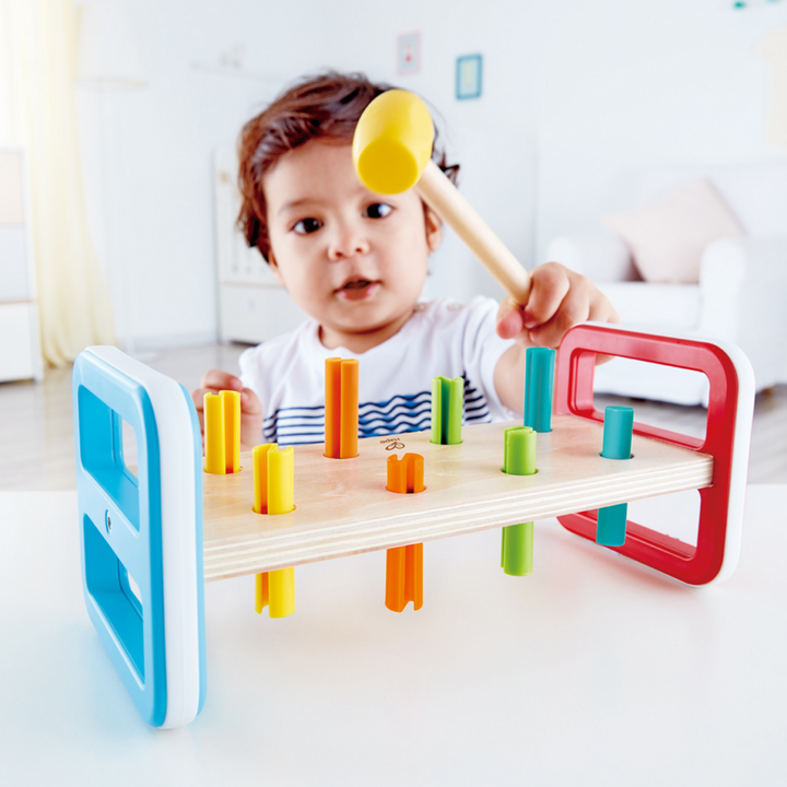 Banc à marteler en bois Hape arc-en-ciel avec maillet et chevilles colorées
