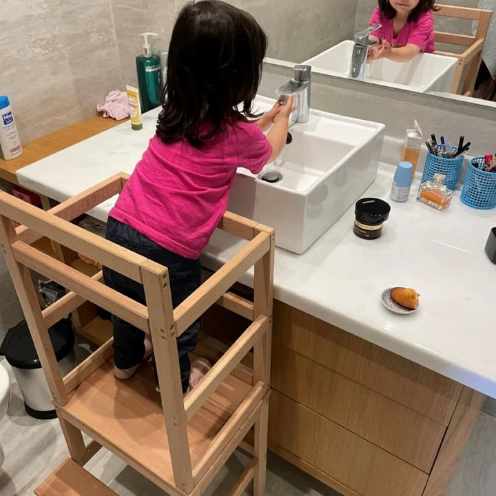 Enfant utilisant une tour d'apprentissage sécurisée dans une cuisine